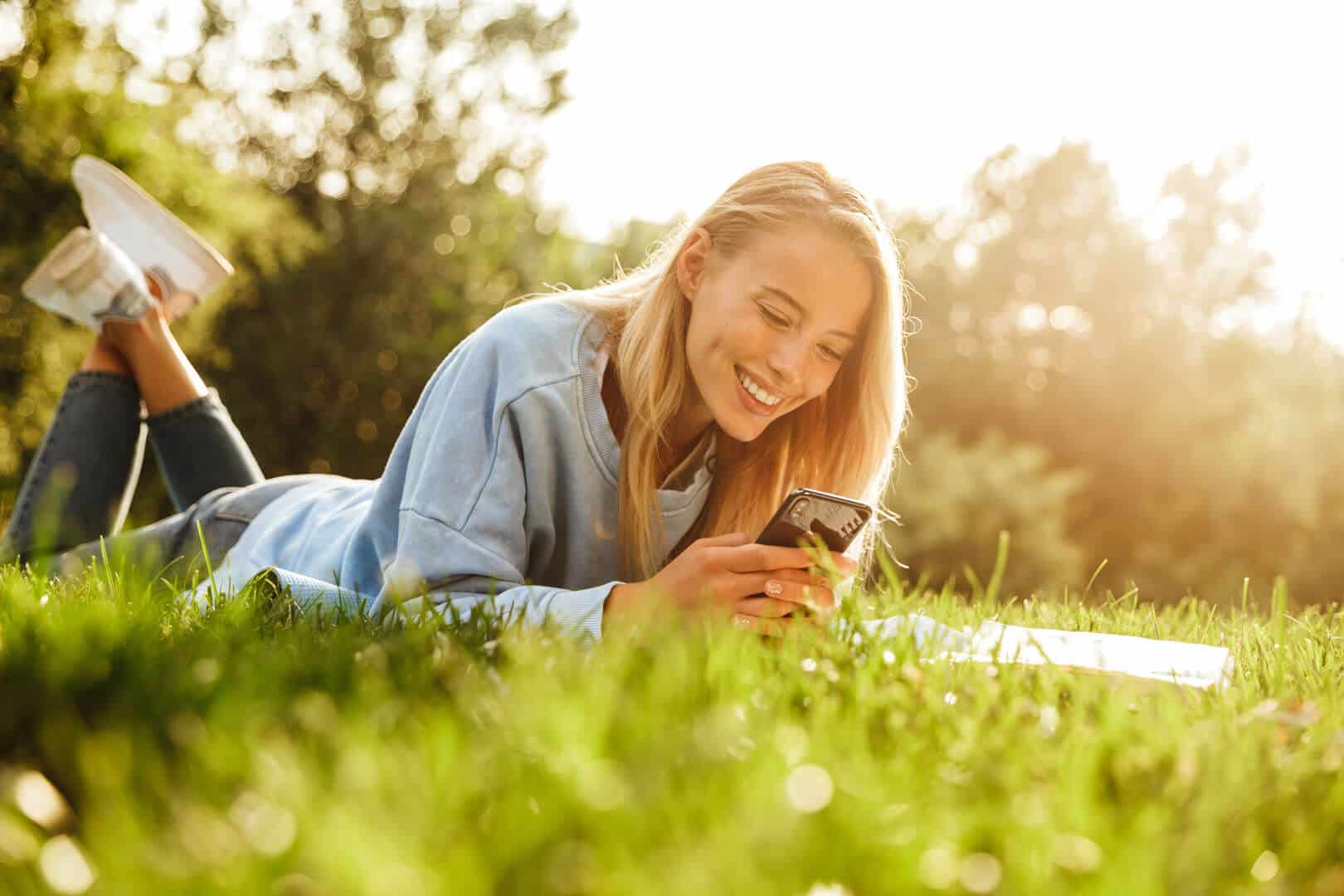 femme allonge herbe sur smartphone